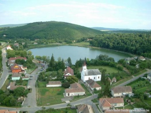 Légifotó a Bánki-tóról. Előtérben a község házai, közöttük a templom. A háttérben dombos, erdős vidék látható.