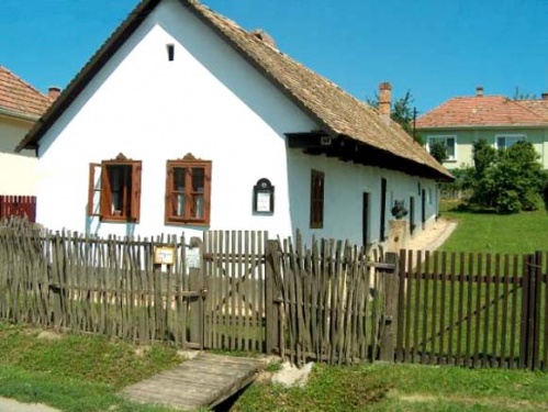 N�dtet�s h�z, feh�rre meszelt falakkal, barna ablakokkal. El�tte l�cker�t�s.