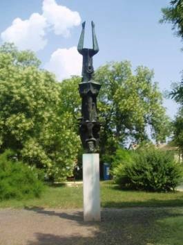 Laluja András busó szobra a mohácsi Kóló téren, háttérben fákkal, parkosított környezetben.